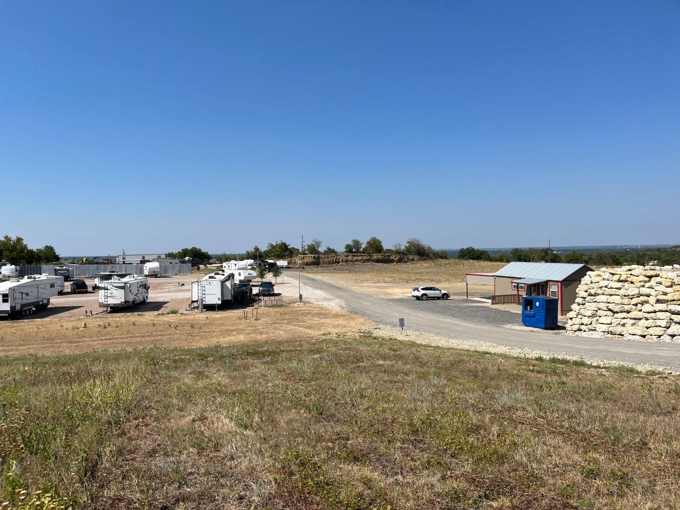 Aledo RV Community seen from the hilltop — gravel pads, the community office, and open Texas country beyond